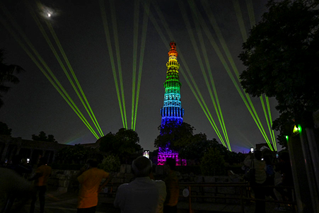 Qutub Minar illuminated in vibrant lights during the evening sound and light show in Delhi.

