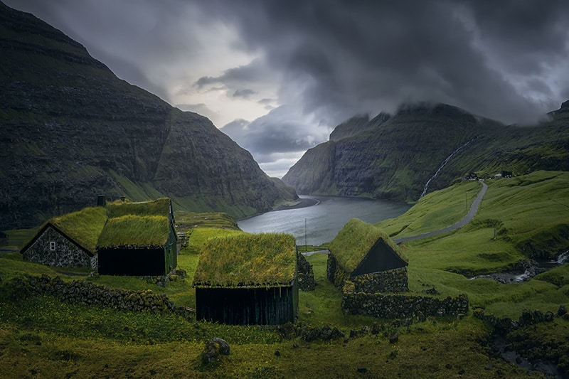 Scenic view of Saksun village surrounded by towering mountains and a tranquil lagoon in the Faroe Islands