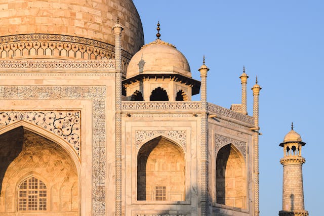 This detailed image showcases the exquisite craftsmanship of Mughal artisans, with semi-precious stone inlays and Arabic calligraphy adorning the white marble surface.
