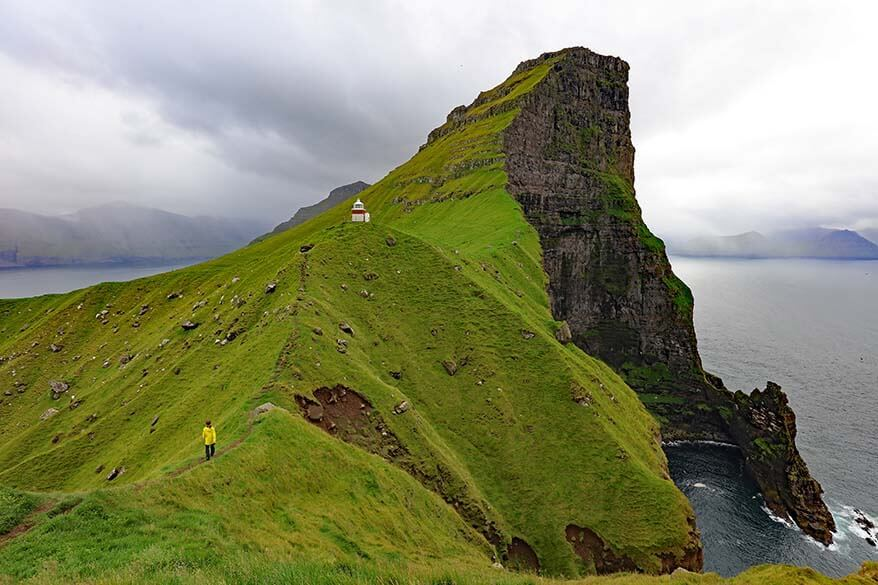 Hikers trekking along a rugged mountain trail overlooking dramatic cliffs in the Islands