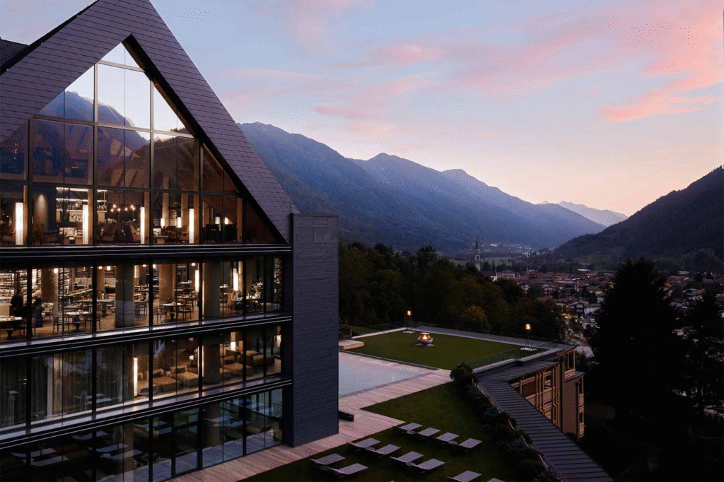 Luxurious Alpine wellness resort surrounded by snowy mountains and pine trees, with an outdoor spa and panoramic views.