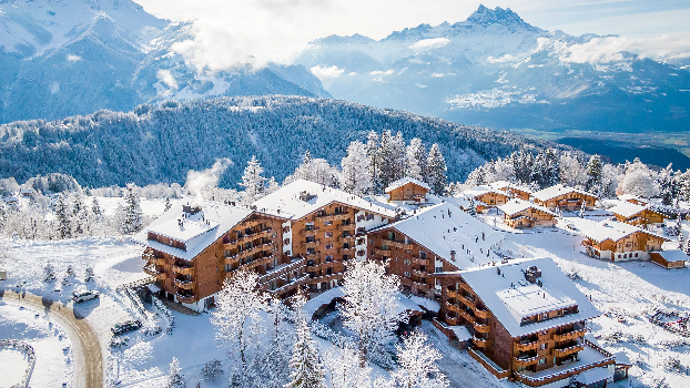 Ski-in ski-out resort in the Swiss Alps with direct slope access, luxury chalets, and skiers outside the lodge