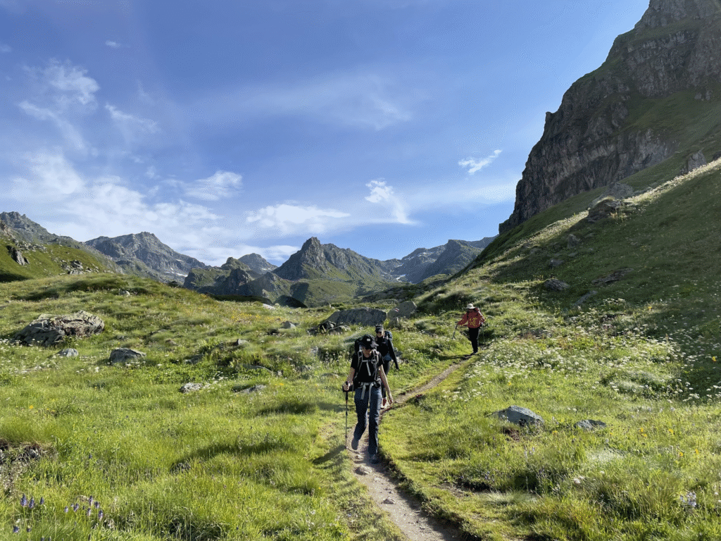 Summer hiking retreat in the Swiss Alps with mountain trails, green meadows, wooden lodges, and hikers enjoying panoramic views