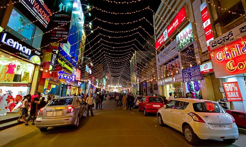 Crowded shopping street in Bangalore’s Commercial Street with shops selling clothes, footwear, and accessories.

