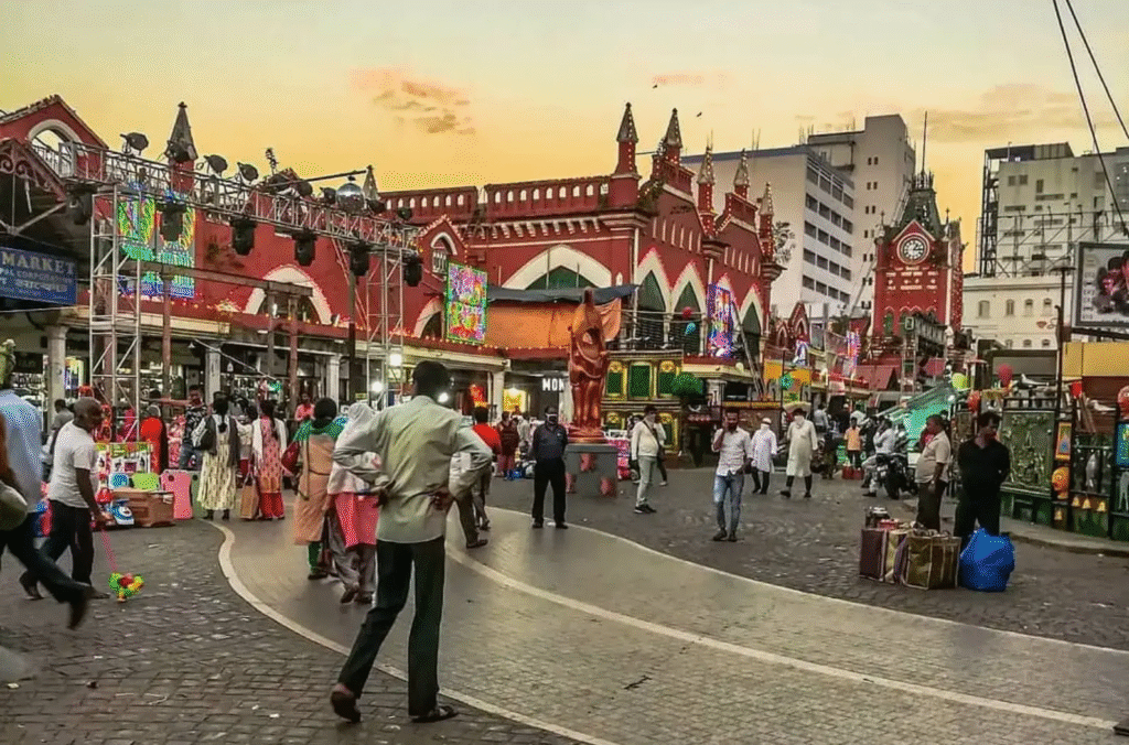 Bustling scene of New Market in Kolkata with shops selling clothing, bags, and local goods.

