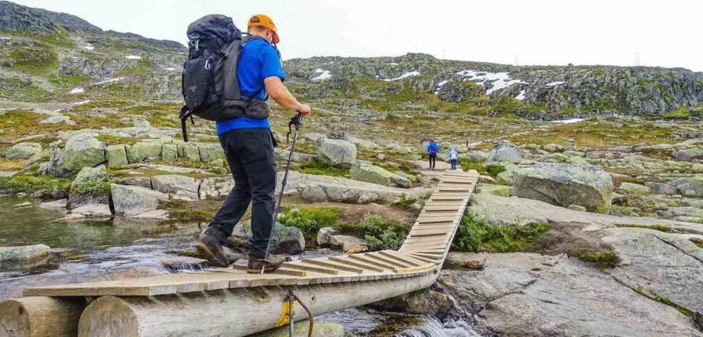 Essential hiking gear laid out for the Trolltunga trail in Norway, including boots, backpack, food, and weatherproof clothing