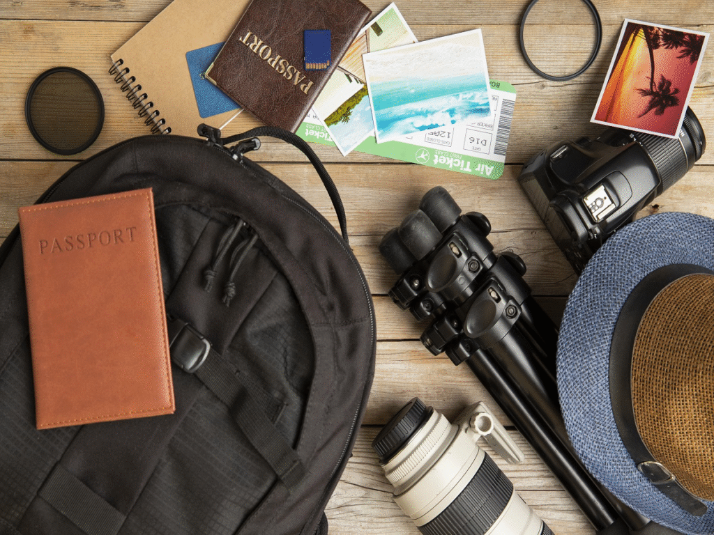 Organized travel essentials spread out on a table, including a passport, maps, gadgets, packing cubes, and safety items